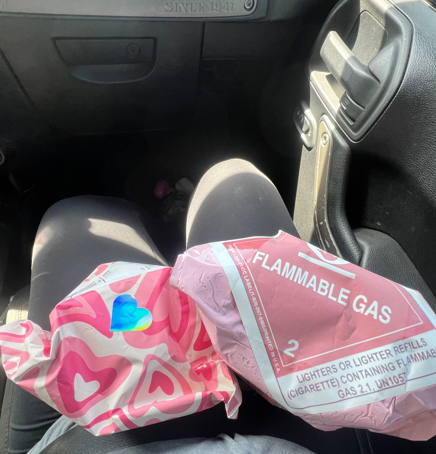 Pink lighter with heart designs wrapped in flammable gas warning paper inside a car.