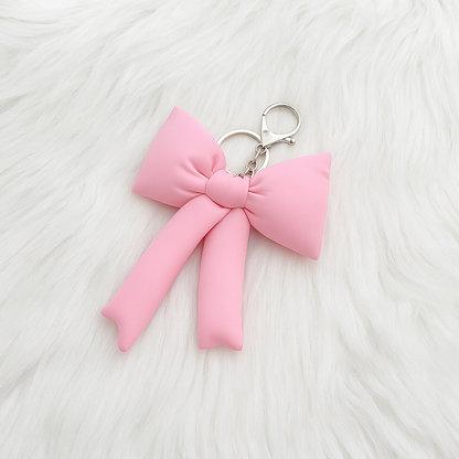 Pink bow keychain on a white textured background